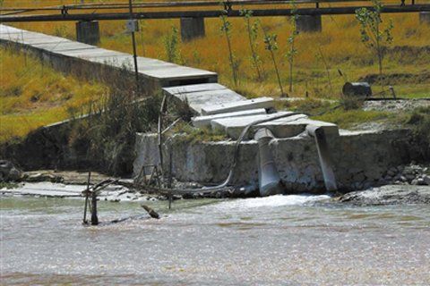 昆明市东川区，一根金属管伸入水池，排放着不明来源的灰白色水，围堰底层铺有防渗膜。